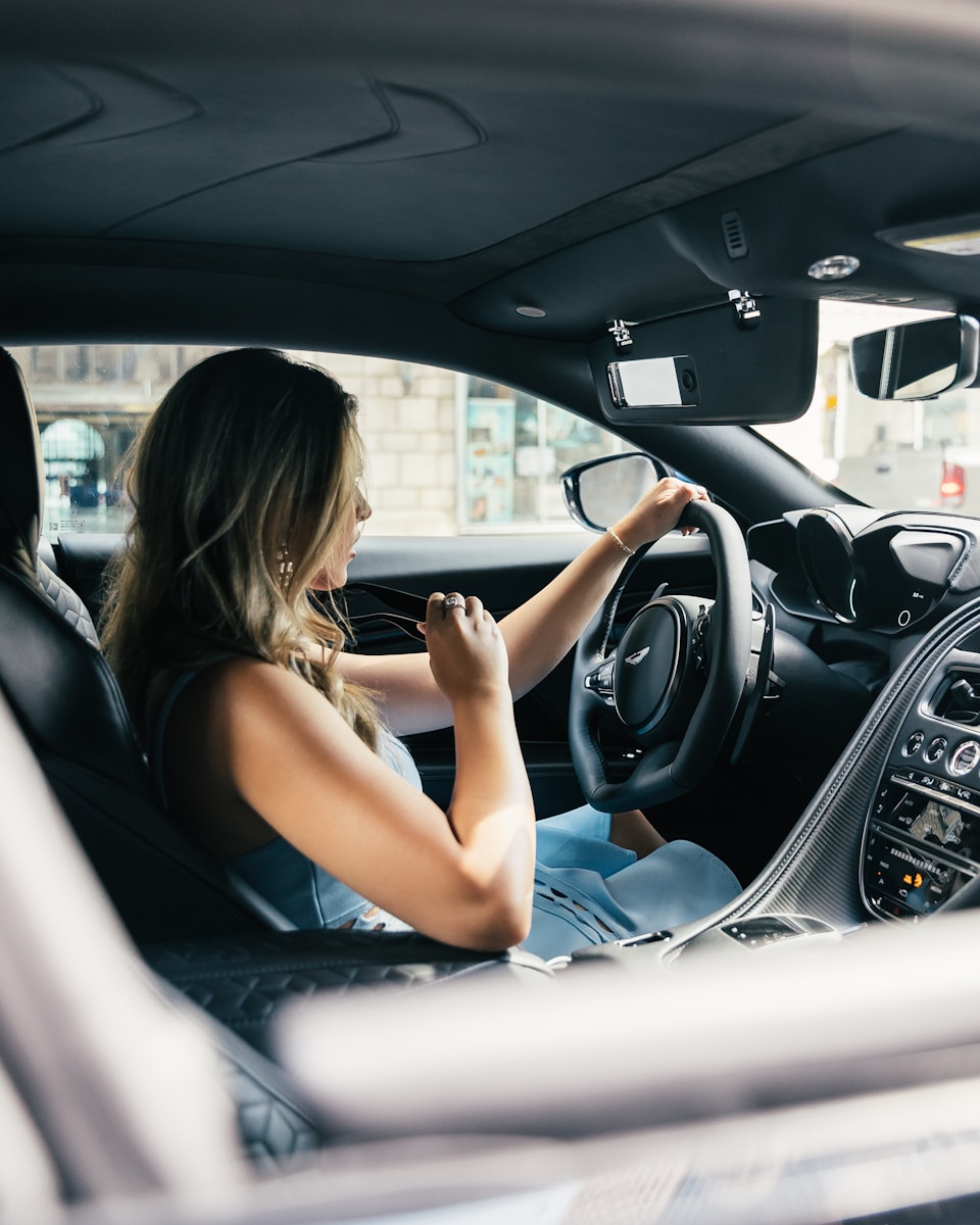 sr-22 woman wearing white tank top driving vehicle during daytime